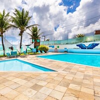 Una piscina al aire libre, sombrillas, sillones reclinables de piscina