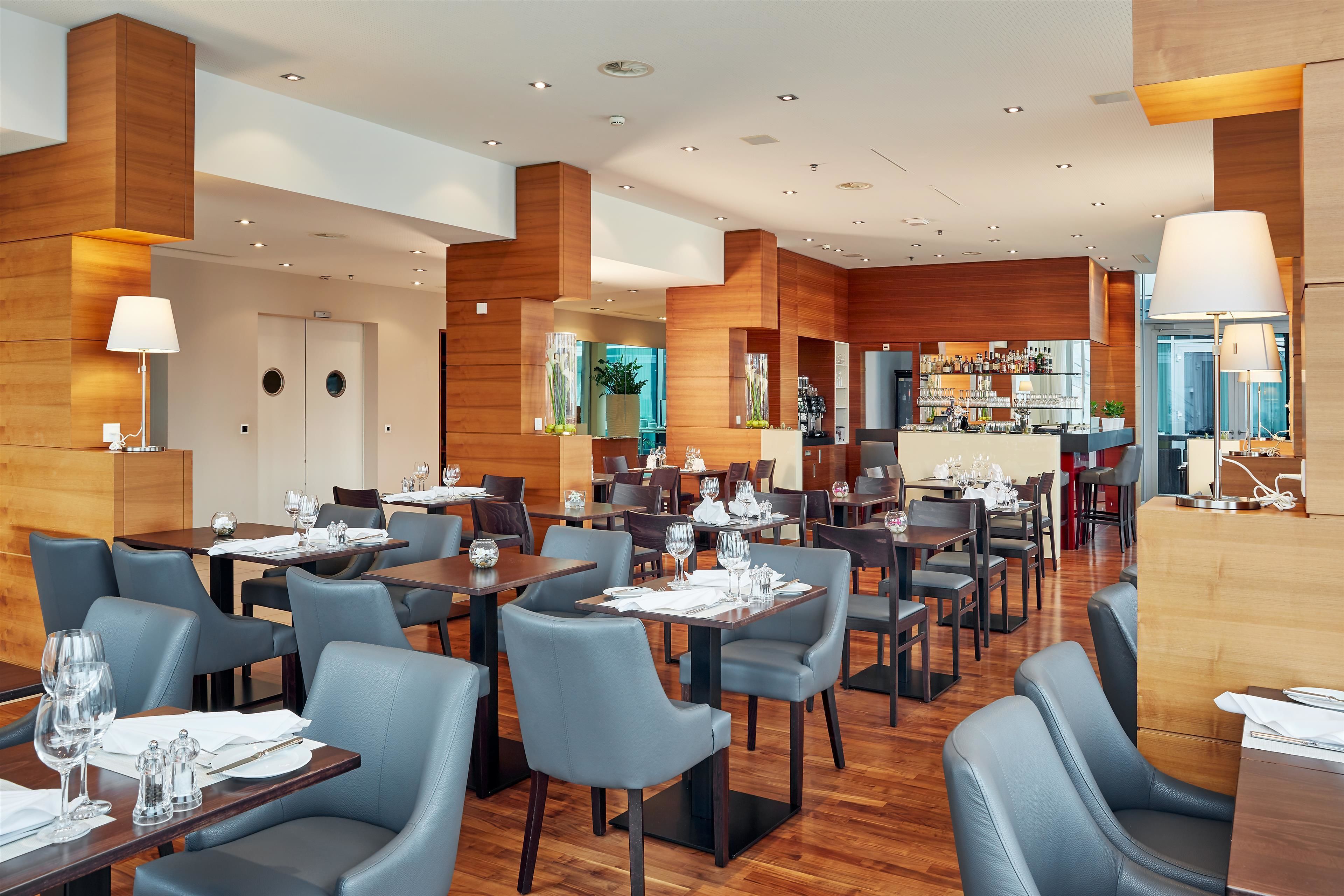Un restaurante moderno con paneles de madera, varias mesas y sillas.