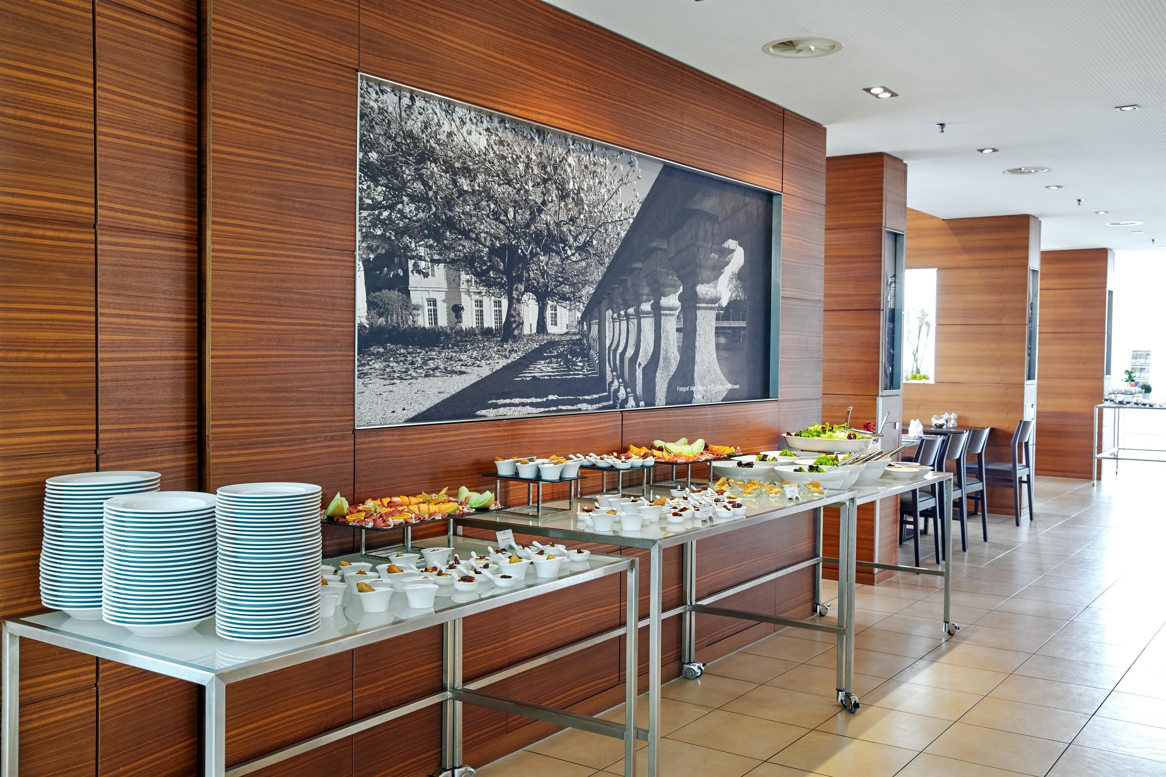 Ein Buffet mit mehreren Servierstationen, ein großformatiges Schwarz-Weiß-Foto an der Wand und ein modernes Interieur.