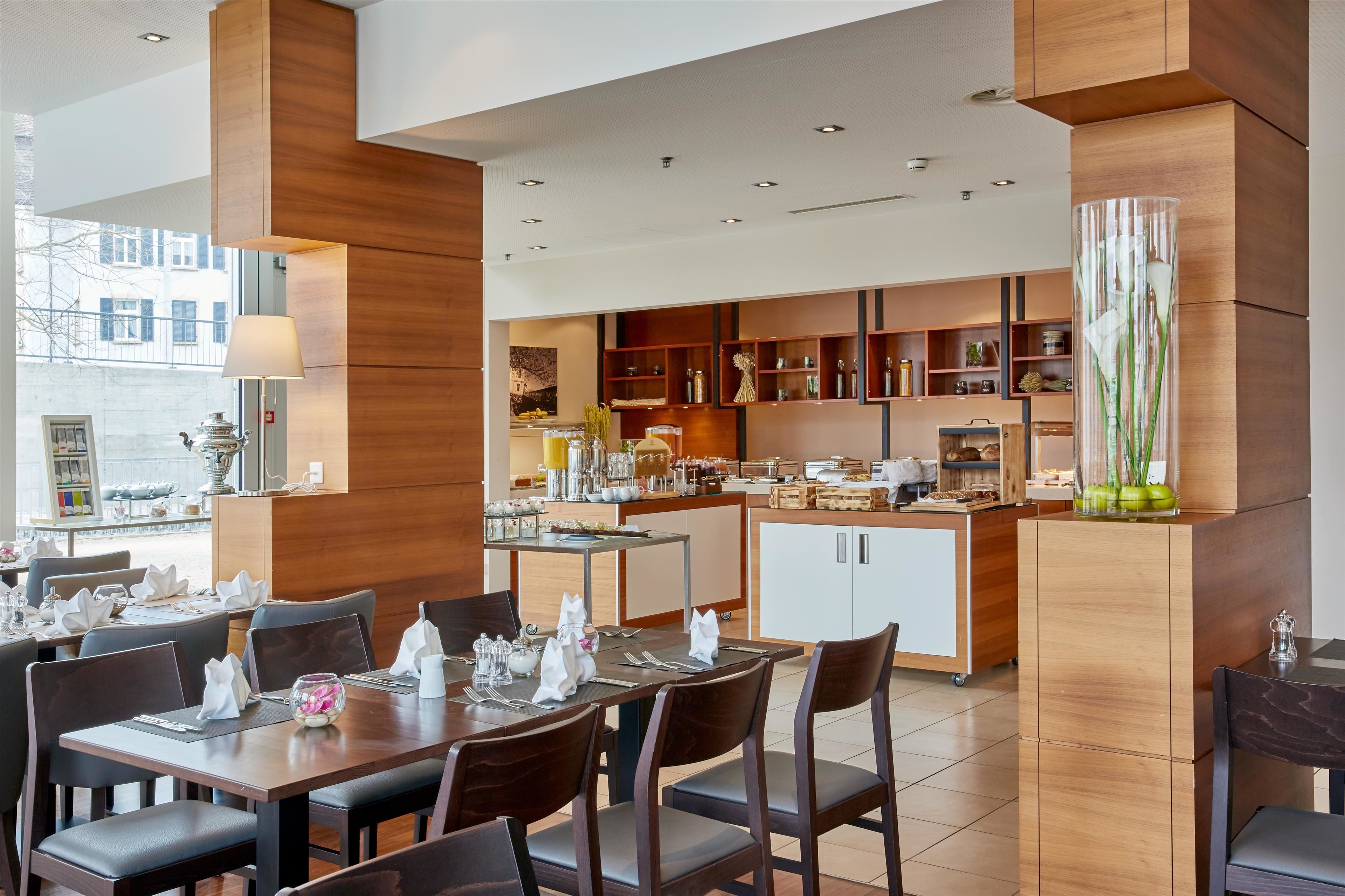 Un espace repas moderne, avec des meubles en bois et une cuisine en arrière-plan.