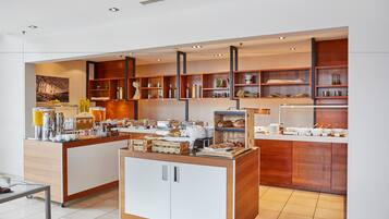 Una barra de desayuno moderna con diversos alimentos y bebidas, estantes de madera con objetos decorativos y un diseño limpio y minimalista.