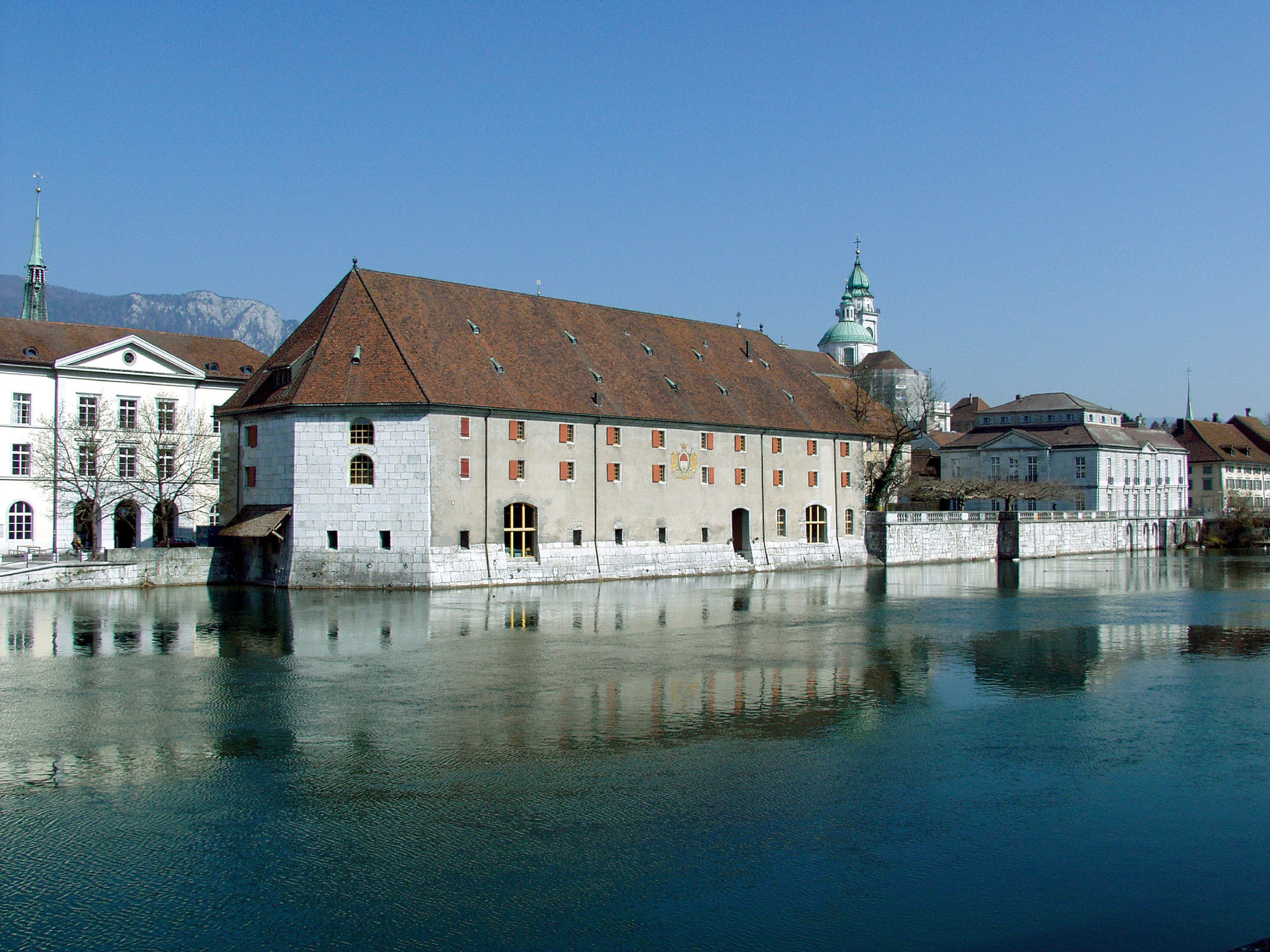 Un bâtiment historique doté d’une tour imposante et d’une vaste étendue d’eau au premier plan.