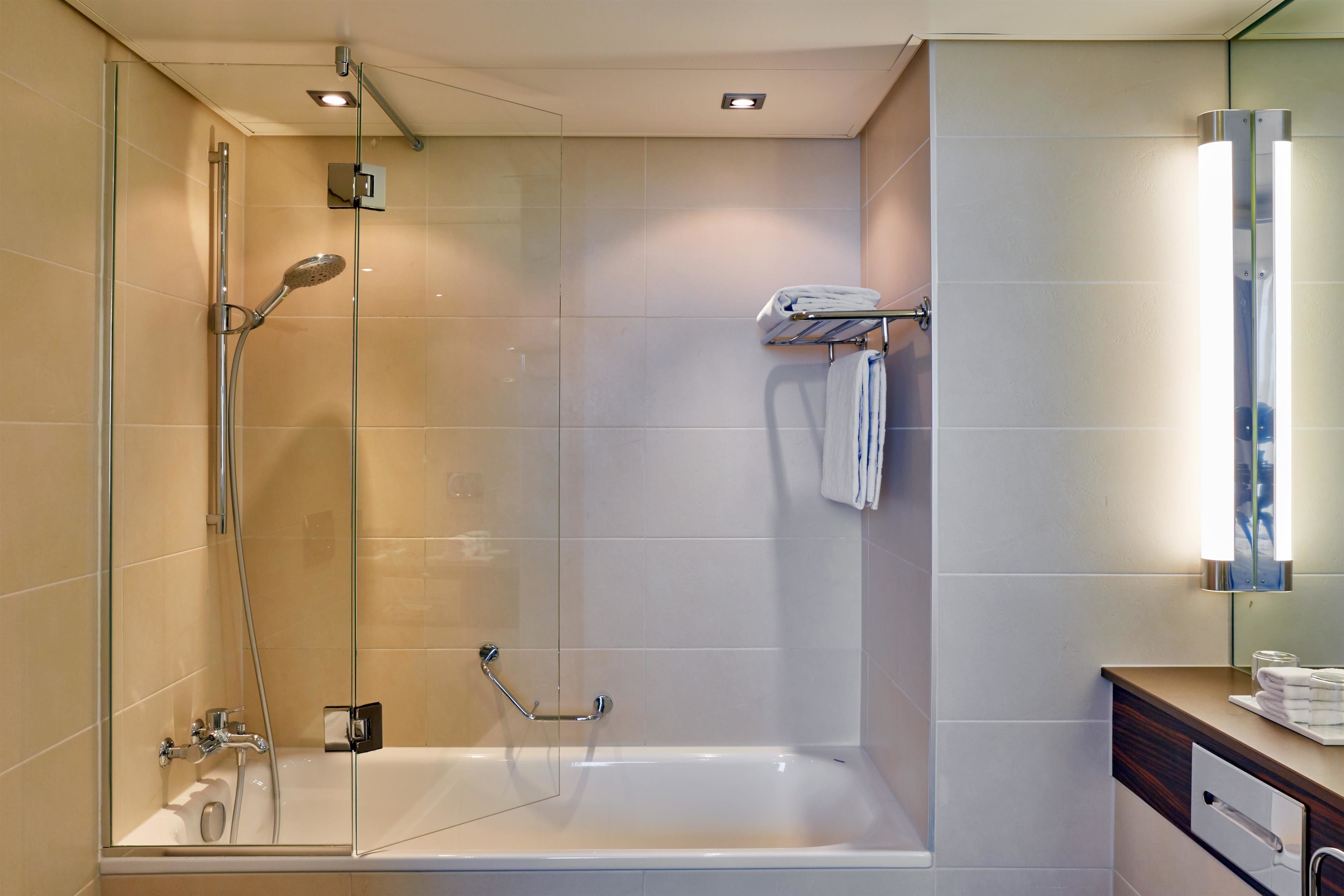 Een moderne badkamer met een douchecabine van glas, een wit ligbad en een wastafel met spiegel.