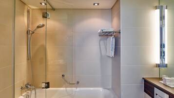 Een moderne badkamer met een douchecabine van glas, een wit ligbad en een wastafel met spiegel.