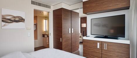 A modern hotel room with a large bed, wooden wardrobe, and a flat-screen TV.