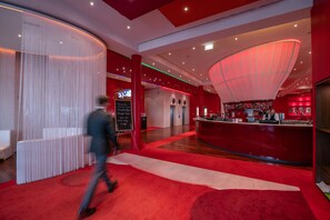 Relax and socialize in our vibrant lobby, featuring a curved reception desk and bar area.