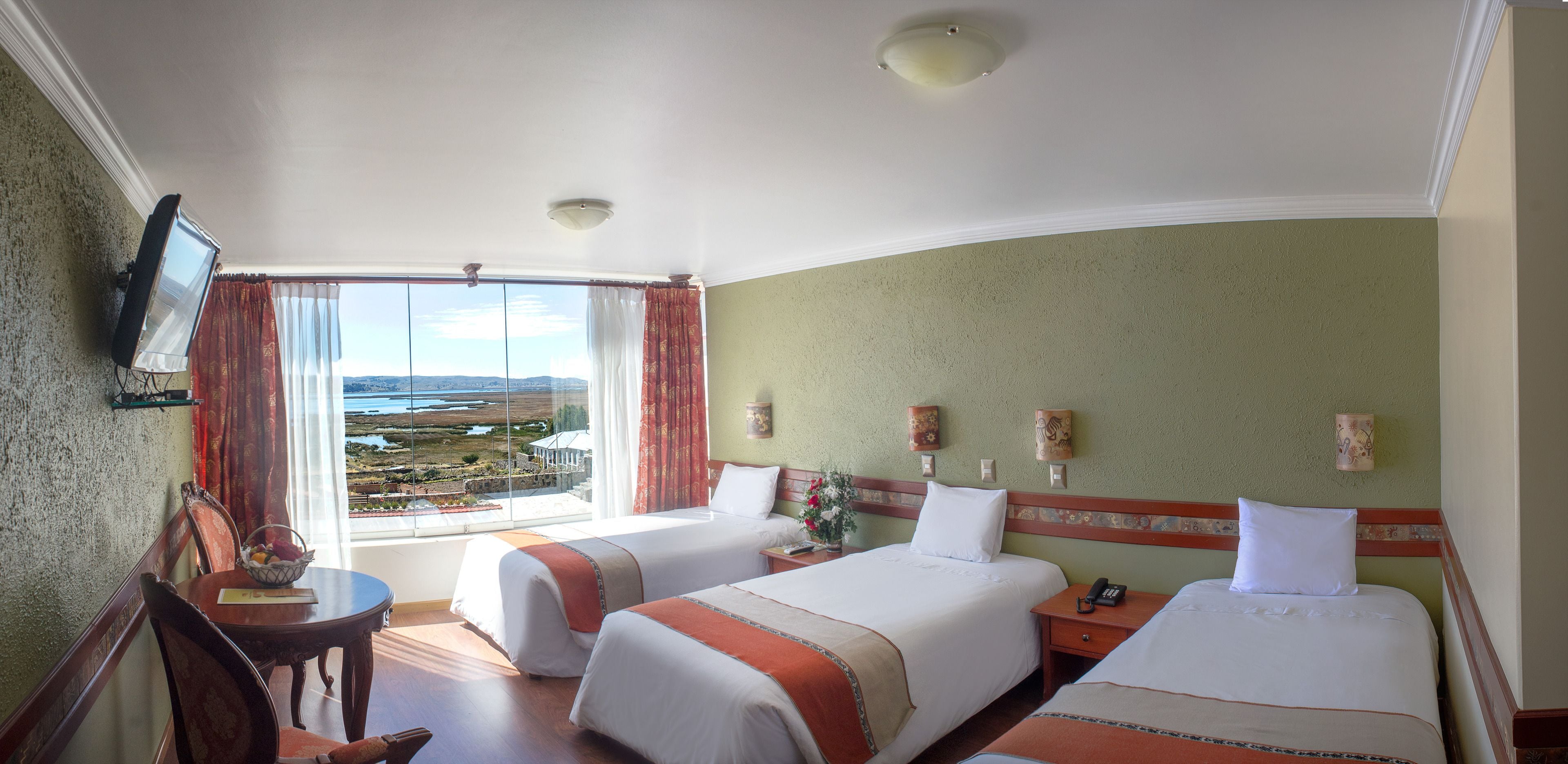 A hotel room with two beds, a desk, a chair, and a view of the landscape.