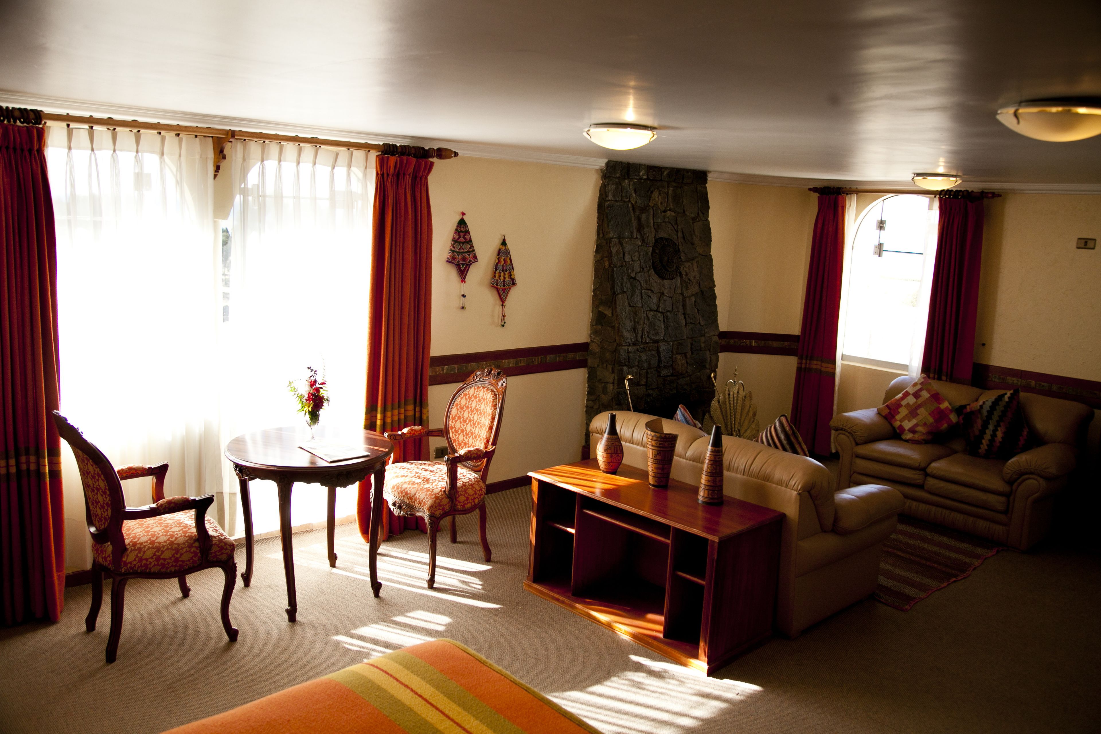 Una sala de estar con chimenea de piedra, un sofá, un sillón y una mesa de centro.