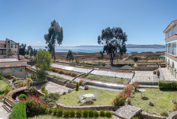 Un jardín ajardinado con un patio, un puente y vista al mar.