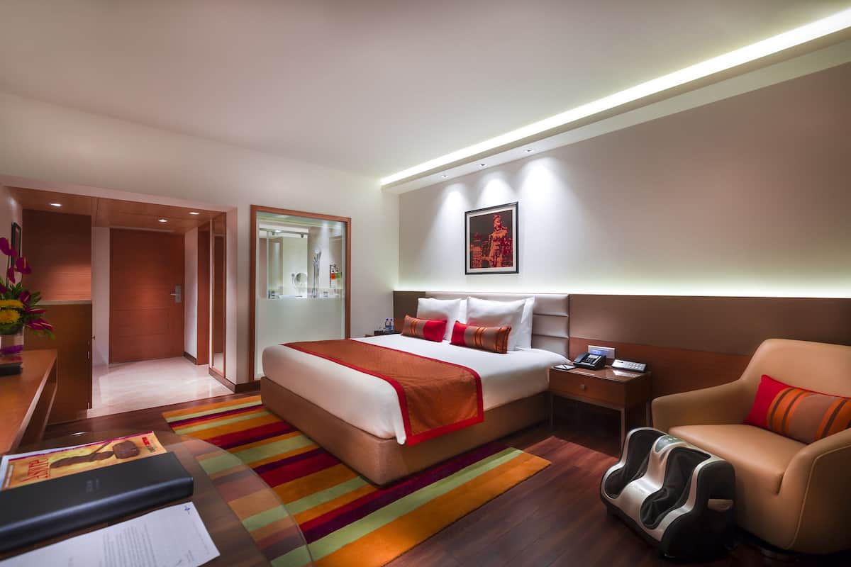 Ein Hotelzimmer mit Bett, Massagesessel, Schreibtisch mit Computer und Nachttisch mit Telefon.