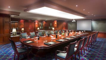 A conference room with a long table, chairs, and a projector screen.