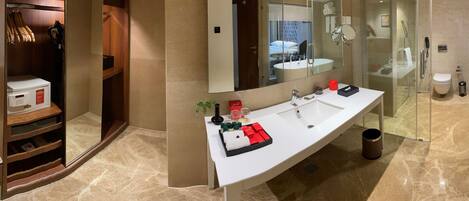 Un baño moderno con un espejo grande, dos lavamanos, zona de ducha y vestidor con calefacción.