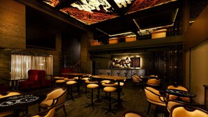 A bar area with multiple seating options including bar stools and chairs, a bar counter, and a ceiling with geometric light fixtures. - Grand Chennai by GRT Hotels (Chennai)