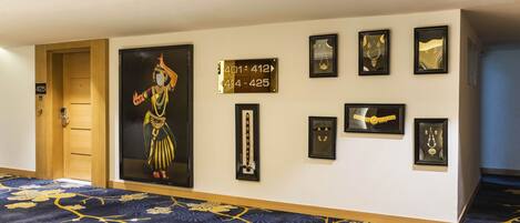A hallway with a carpeted floor, a door labeled 425, and several framed items on the wall.