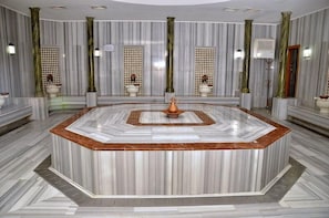 A marble-floored lobby with a central fountain, columns, and patterned wall tiles.