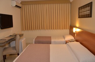 Habitación de hotel con dos camas, un escritorio con silla, aire acondicionado y televisor montado en la pared.