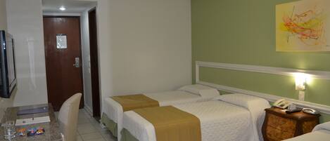 A hotel room with two beds, a desk with a chair, a television, and a wall-mounted phone.