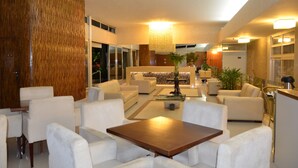 A modern hotel lobby with a seating area, a central coffee table, and a large wooden accent wall. - Arituba Park Hotel (Natal)