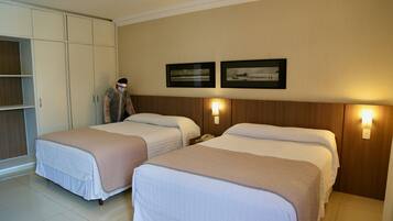 Habitación de hotel con dos camas, un armario y dos luces fijadas a la pared.