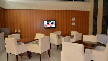 Habitación de hotel con pared de paneles de madera, un televisor de pantalla plana montado sobre una mesa y sillas de madera, y un cartel que indica una zona para fumadores.