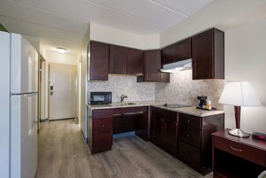 Cocina compacta con armarios de madera oscura, microondas, lavamanos y una pequeña encimera.