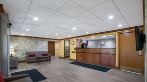 A reception area with a stone wall, a reception desk, a clock, and a TV mounted on the wall.