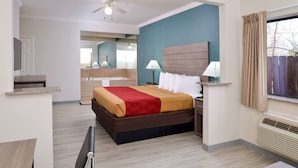 A hotel room with a bed, bedside table, lamp, and a view of a wooden deck. - Econo Lodge Inn & Suites Port Arthur near Sabine Pass (Port Arthur)