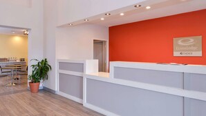 A reception area with a red accent wall, a reception desk, and a seating area with a plant. - Econo Lodge Inn & Suites Port Arthur near Sabine Pass (Port Arthur)