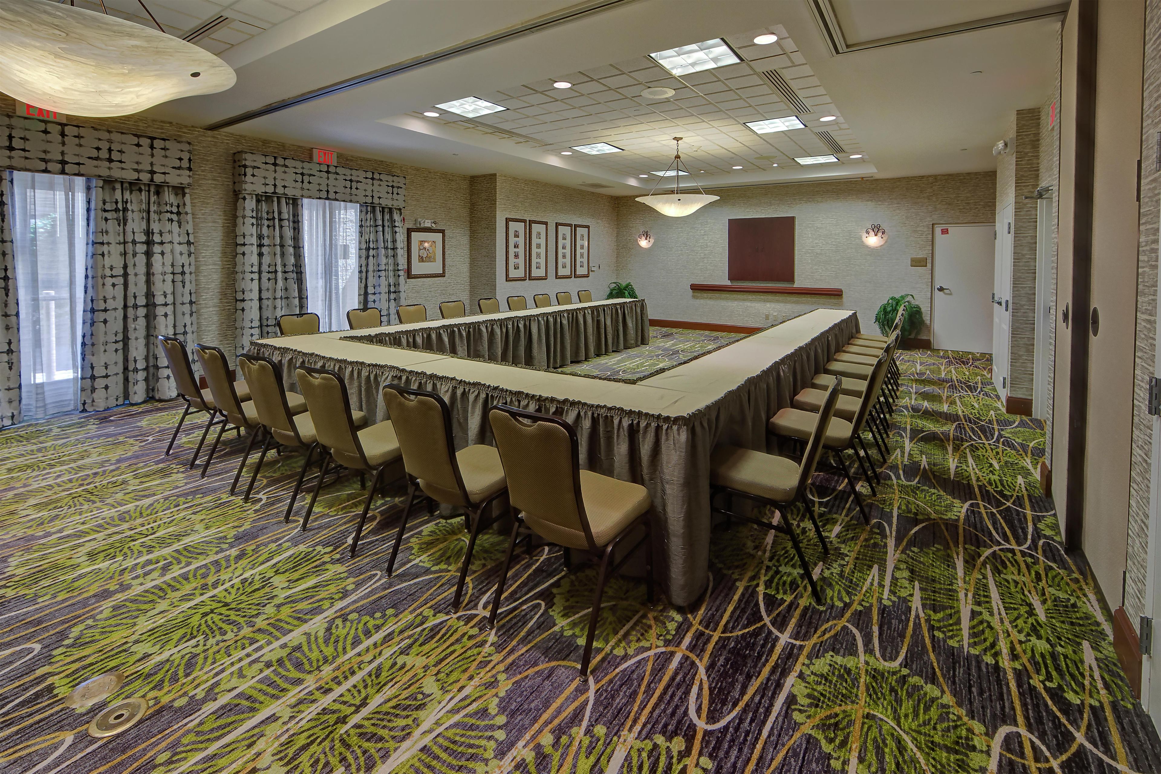 A conference room with a long table, chairs, and a patterned carpet.