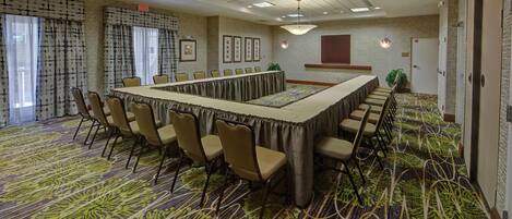 A conference room with a long table, chairs, and a patterned carpet.