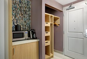 Una kitchenette con microondas, cafetera y un mueble con salpicadero de mármol.