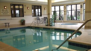 Una piscina interior con agua cristalina, líneas de profundidad marcadas y un letrero de salvavidas.