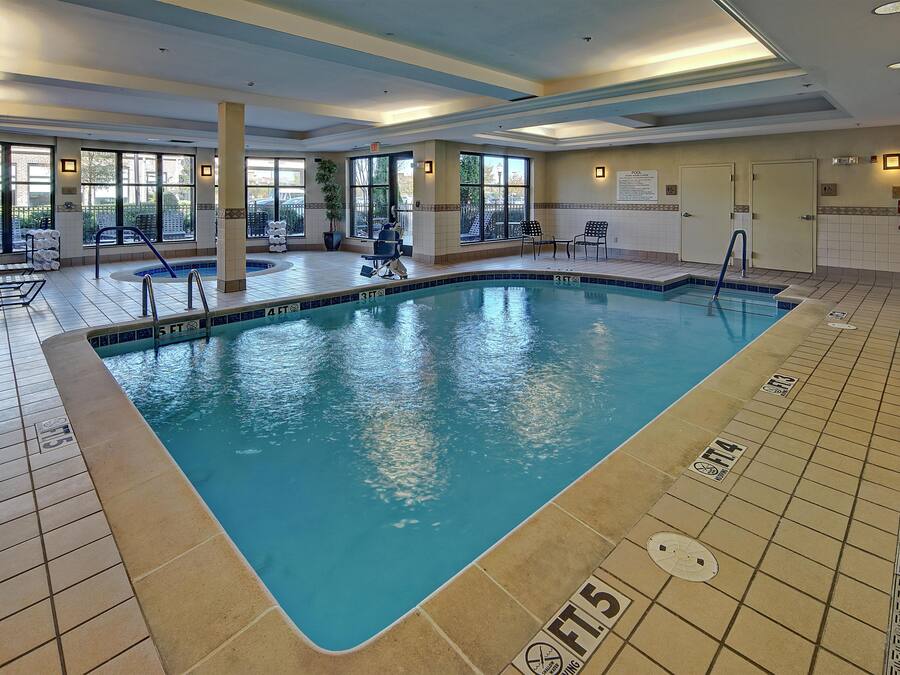 An indoor swimming pool with clear water, marked depth lines, and a tiled floor.
