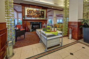 Un vestíbulo de hotel con chimenea, zona de estar y mostrador de recepción.