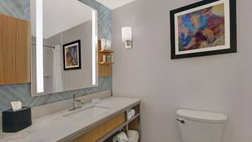 A bathroom with a large mirror, a sink, a toilet, and a shelf with toiletries.
