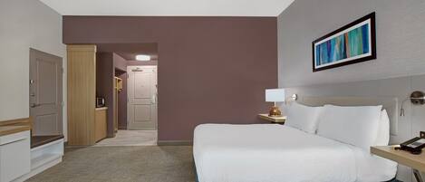 Una camera d'albergo con un letto, un comodino, una lampada e un quadro appeso al muro.