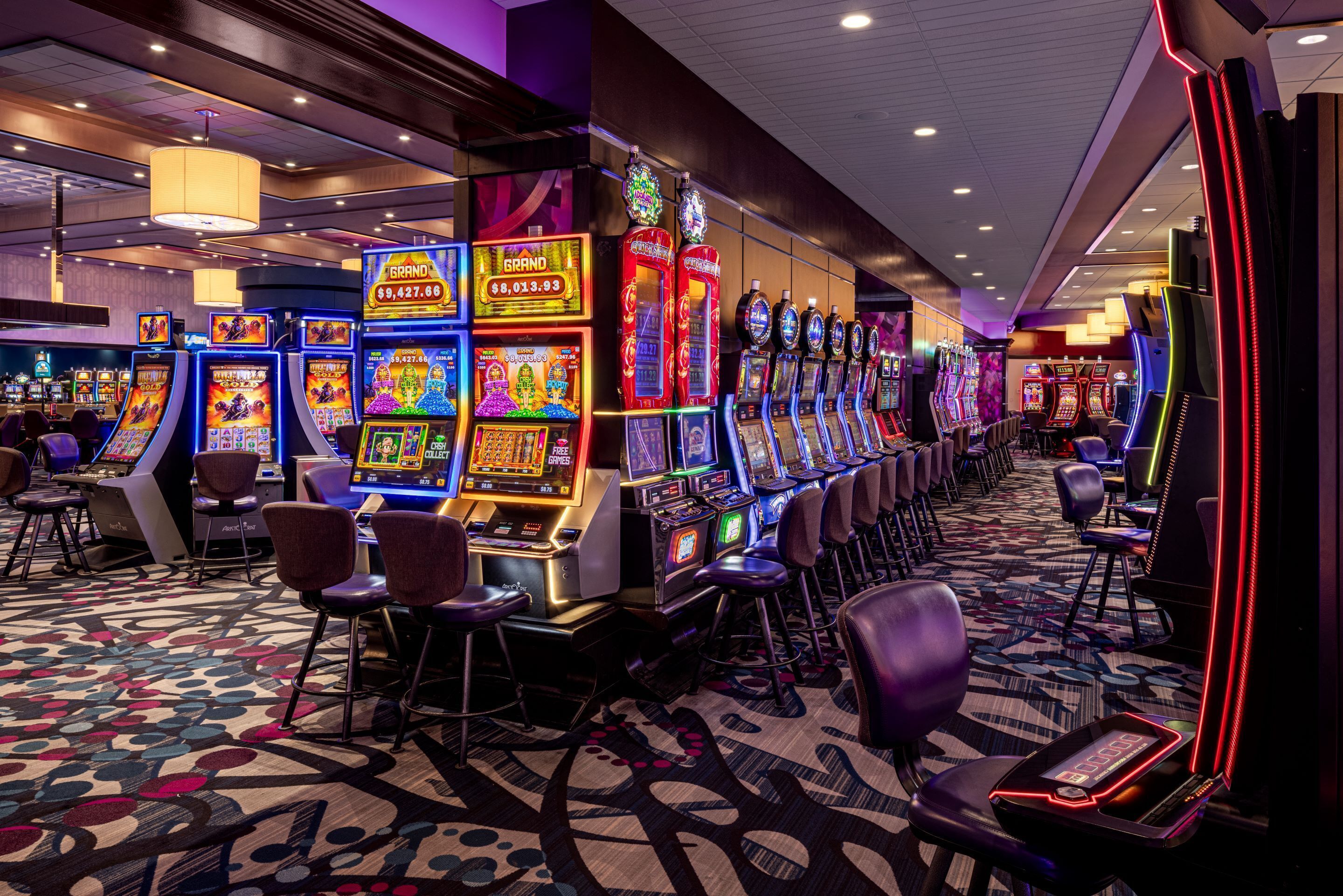 A casino with multiple slot machines and bar seating.