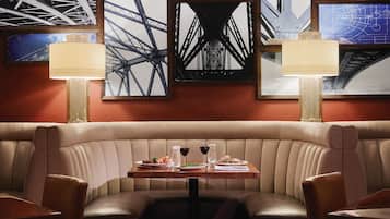 A restaurant with a booth seating area, a table with plates and glasses, and framed pictures on the wall.