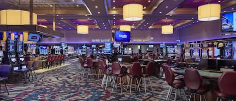A casino with multiple gaming tables and chairs, a high-limit poker room, and a Harrah's sign.
