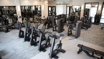 Un gimnàs amb diversos equips d'exercici, incloent cintes de córrer, aparells de musculació i peses lliures.