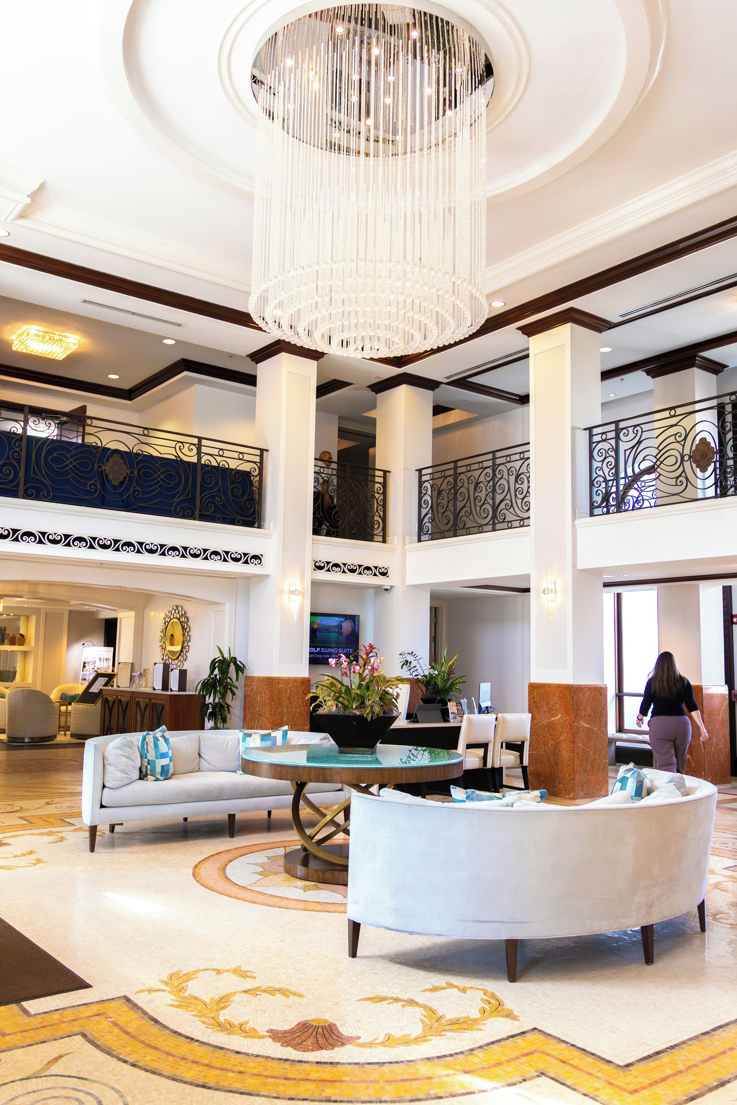 A spacious lobby with a grand chandelier, a reception desk, and a seating area with a coffee table.