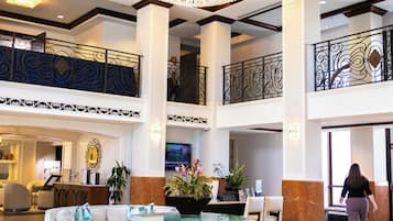 A spacious lobby with a grand chandelier, a reception desk, and a seating area with a coffee table.