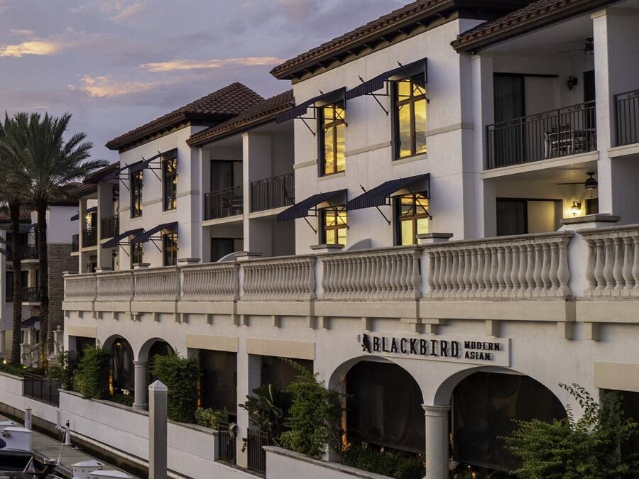 A multi-story hotel with a white facade, balconies, and a sign reading "BLACKBIRD Modern Asian."
