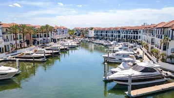 A marina with boats docked along a canal, surrounded by multi-story buildings with red-tiled roofs and balconies.