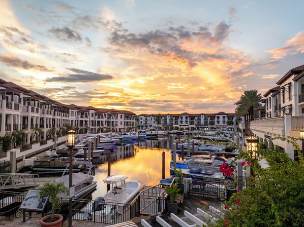A marina with boats docked, a waterway, and buildings with balconies and railings.