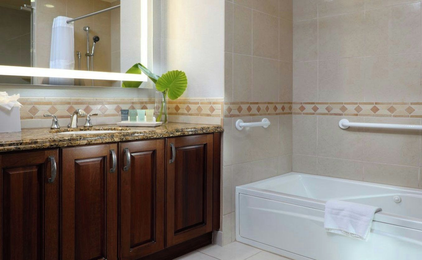 A bathroom with a bathtub, a vanity with a mirror, and a shower area.