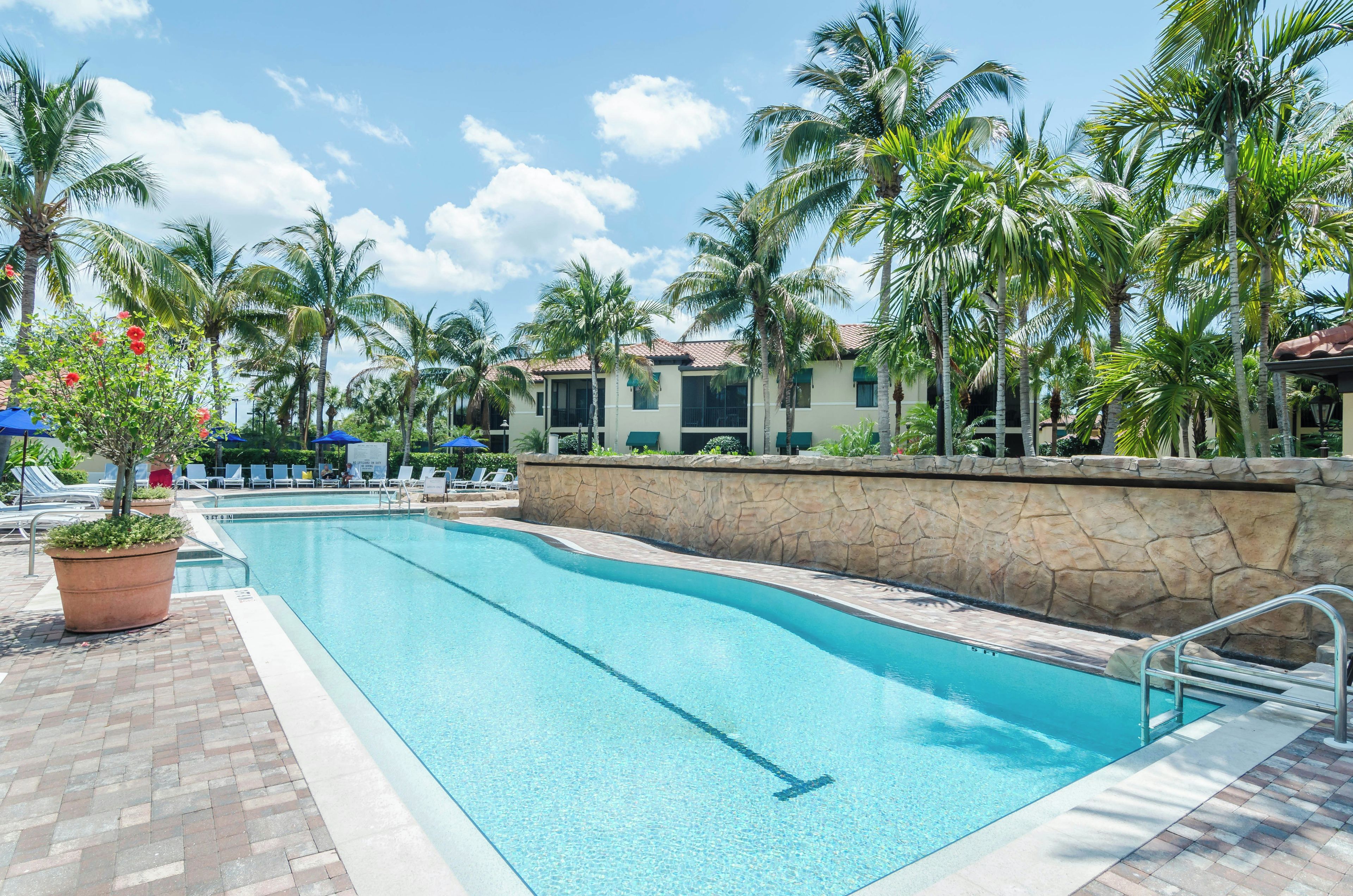 Ein Pool mit einer Steinmauer und Palmen im Hintergrund.