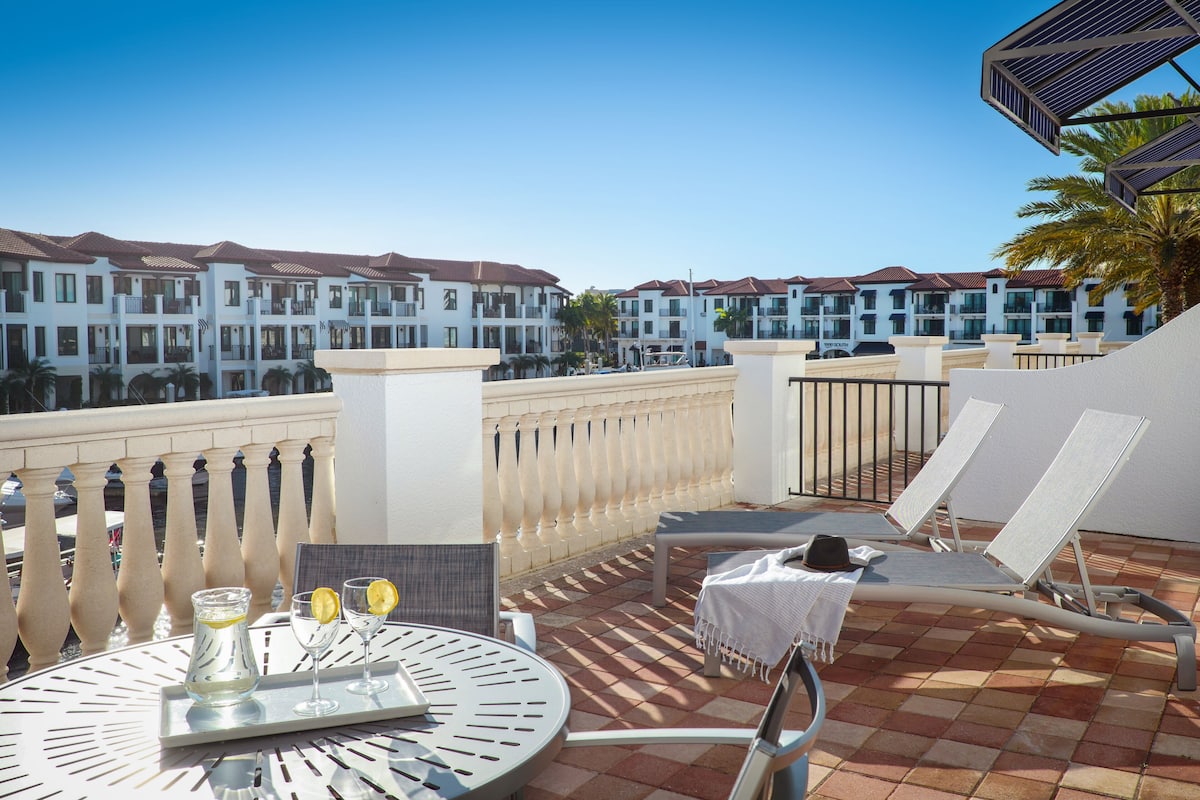 A terrace with a table, chairs, and a view of hotel buildings.