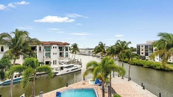A waterfront property with a swimming pool, a marina with boats, and modern buildings.