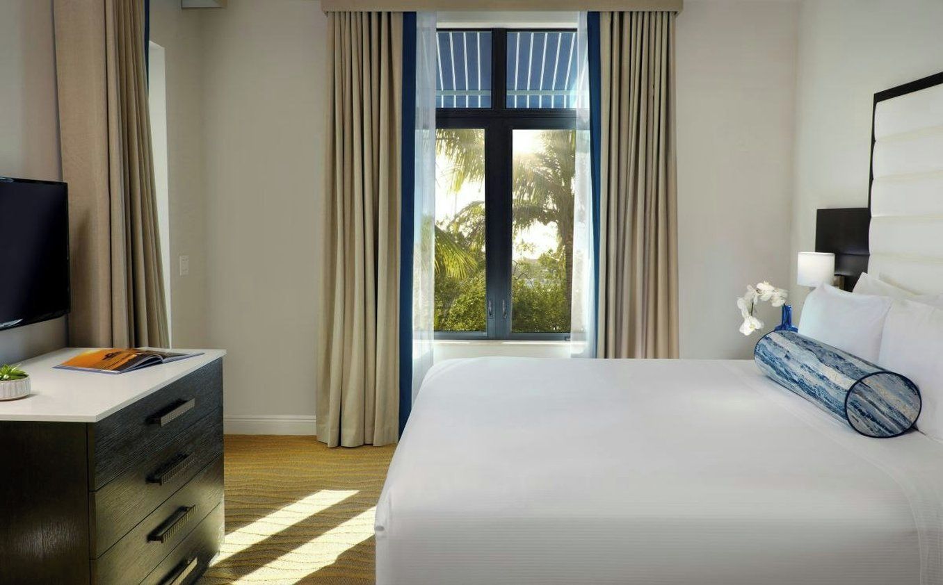 Een hotelkamer met een bed, een bureau met een televisie en een raam met gordijnen.